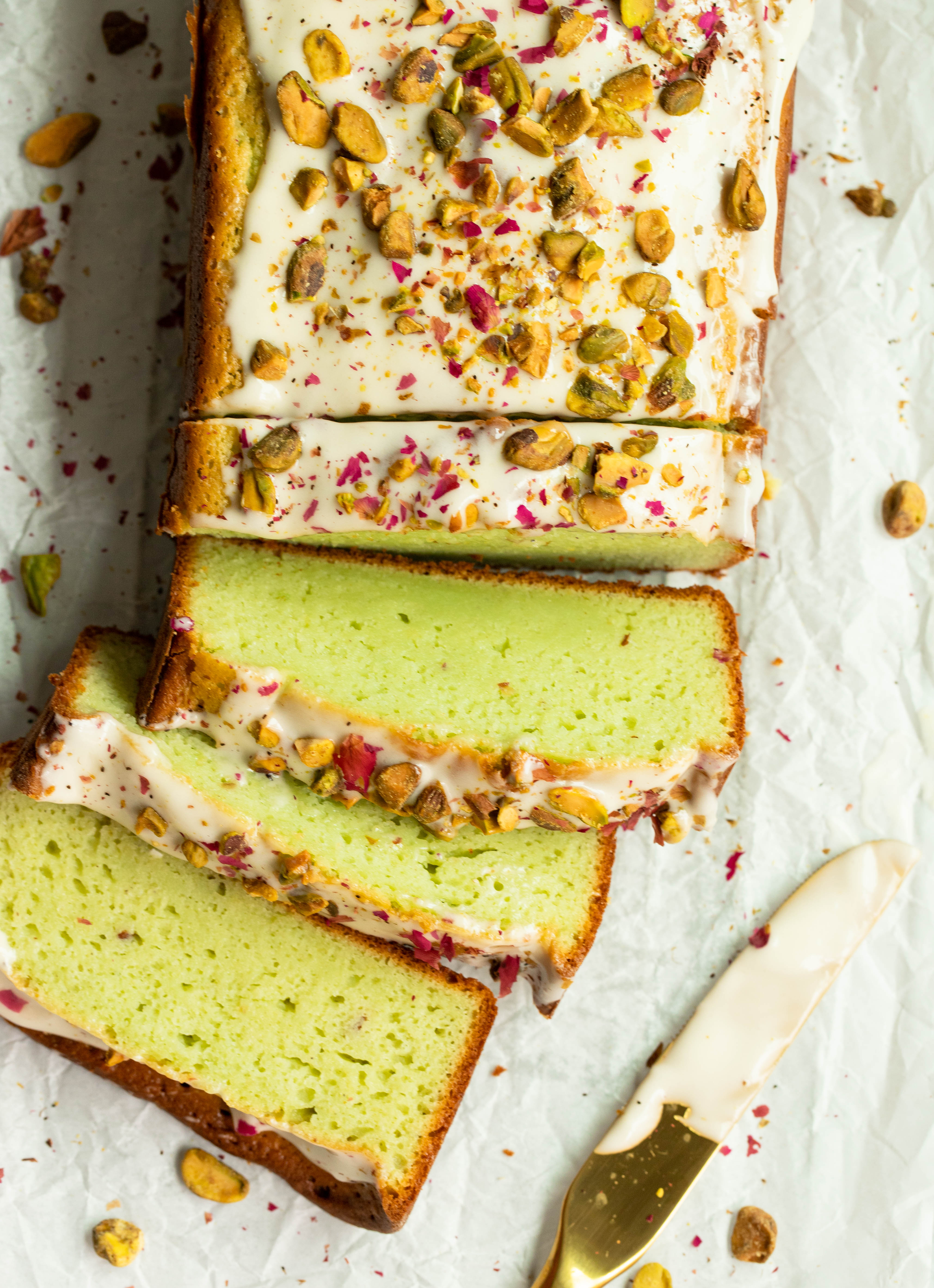 sliced pistachio pudding loaf with cream cheese frosting and toasted pistachios 