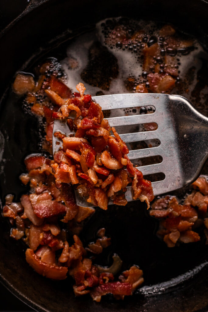 Crisping the bacon in an iron skillet.