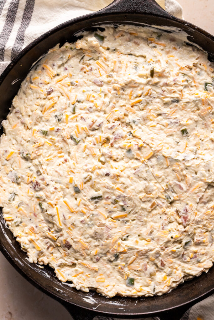 The dip properly spread into the cast iron skillet waiting for its topping right before going into the oven.