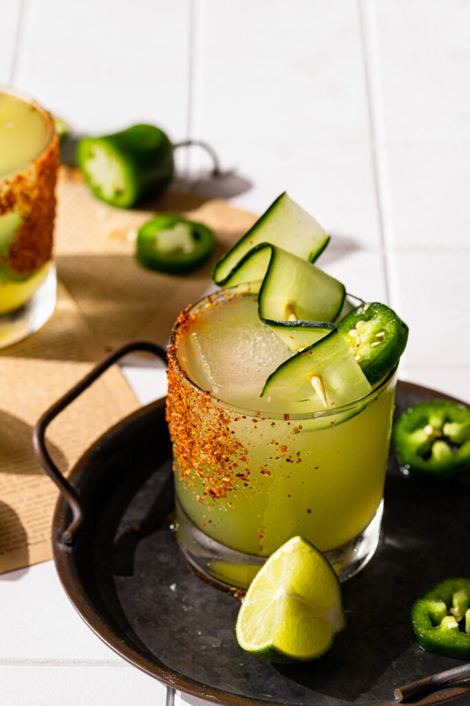 A close up shot of the finished cucumber margarita with a lime wedge sitting next to it.
