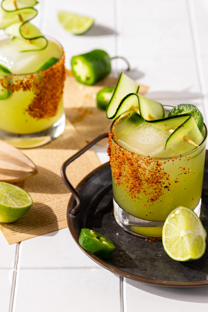 Two spicy margaritas pictured with tajin coated glasses.