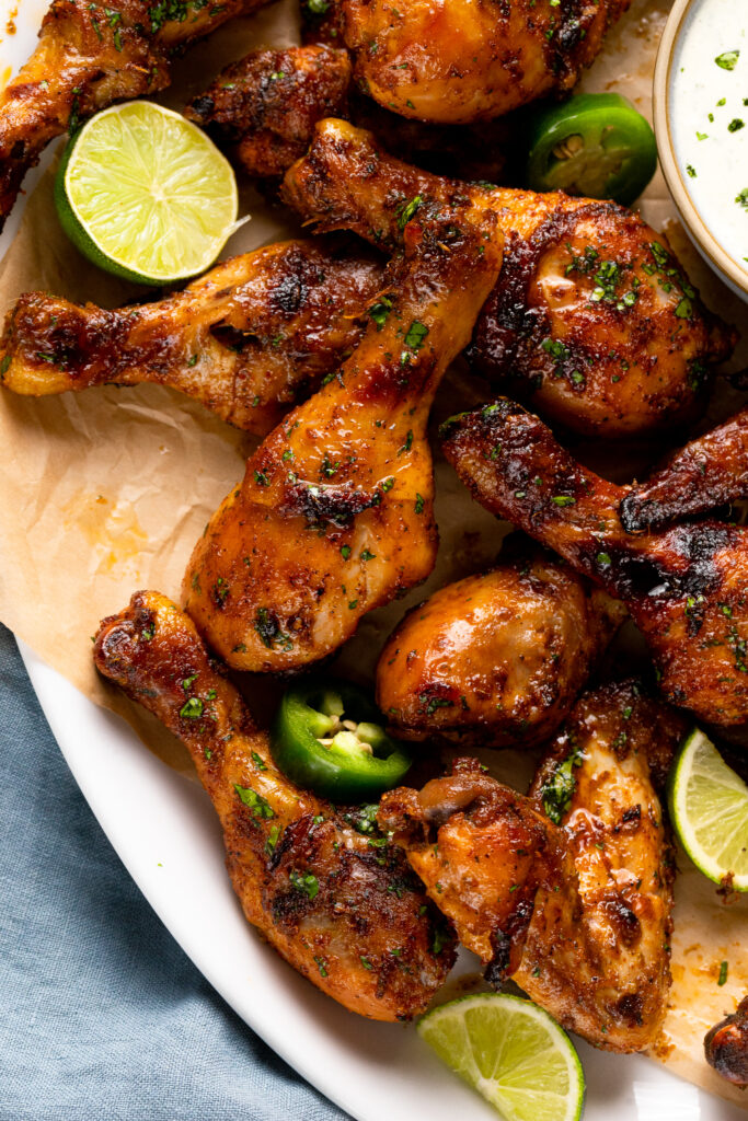 Cilantro Lime Baked Chicken Wings sitting in a serving tray with slices of lime and dip on the side.