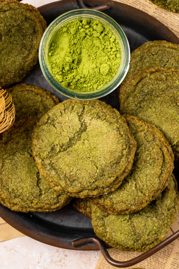 A closer up look at a plate of the matcha cookies along with a small bowl filled with the matcha powder.